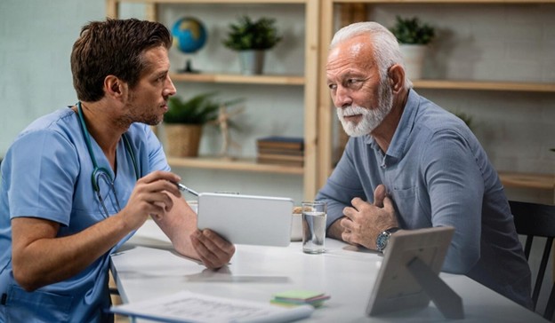 Male nurse showing medical results to senior man on tablet